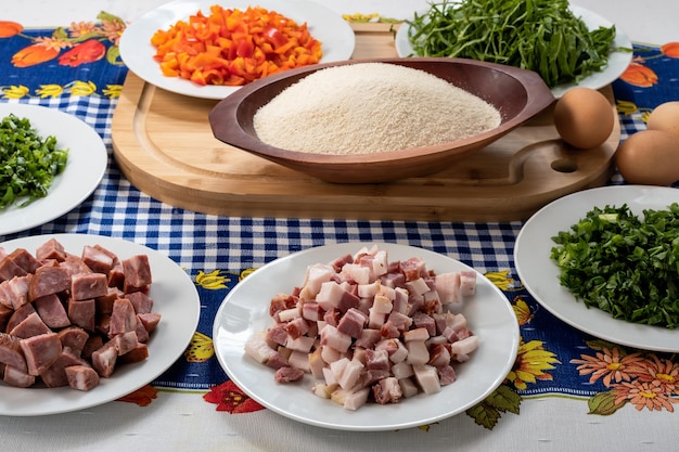 Ingredientes para preparar uma receita bacon repolho pimentão vermelho farinha de mandioca salsa salsa em uma mesa