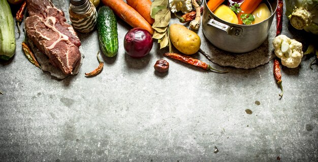 Ingredientes para sopa com legumes, especiarias e carne. Na mesa de pedra.