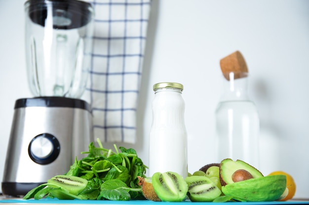 Ingredientes para um smoothie verde. Fundo turquesa de banana, espinafre, sementes de chia, leite de coco em uma jarra de vidro, abacate, uvas. Detox, receita de smoothie para uma dieta saudável.