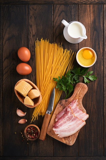 Ingredientes para Pasta Carbonara Traidtional Italian Pasta Carbonara Ingredientes tocino espagueti parmesano y yema de huevo ajo Fondo de mesa antiguo de madera oscura Vista superior Espacio de copia