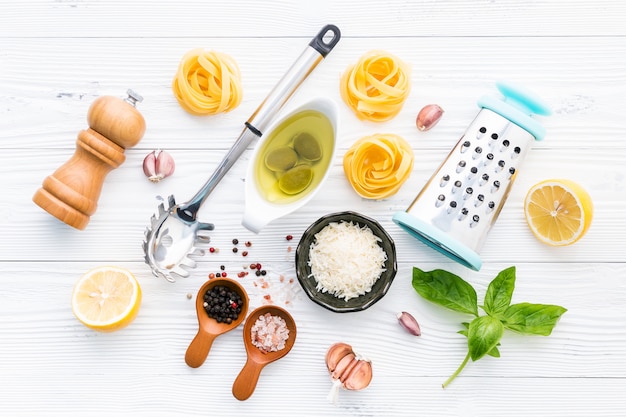 Los ingredientes para las pastas hechas en casa del pesto en el fondo de madera blanco.