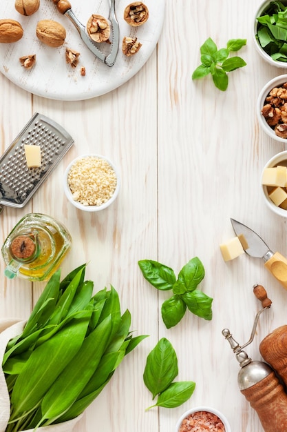 Ingredientes para Pesto de ajo silvestre cocinando deliciosa salsa salada para pasta italiana Ramson hierbas queso nueces albahaca aceite de oliva Vista superior sobre fondo blanco