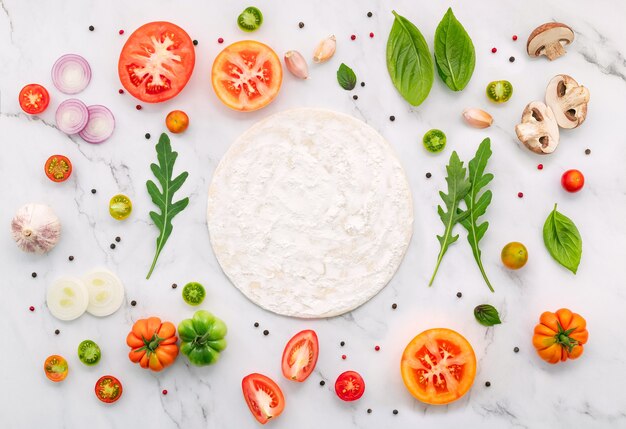 Los ingredientes para la pizza casera sobre fondo de mármol blanco.