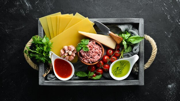 Ingredientes para la preparación de pasta de salsa de tomate Lasagna Sobre un fondo negro Vista superior Espacio libre para el texto