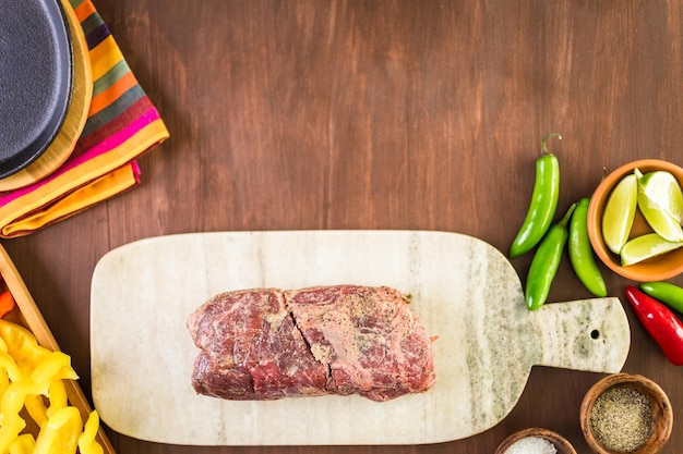 Ingredientes para preparar fajitas de bistec en una mesa de madera.