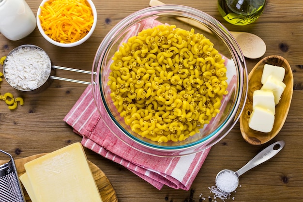 Ingredientes para preparar macarrones con queso en una mesa de madera.