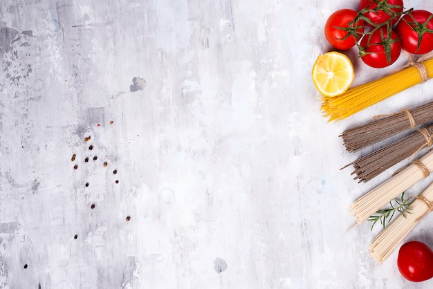 Ingredientes para preparar las pastas y la salsa aislados en el fondo de piedra.