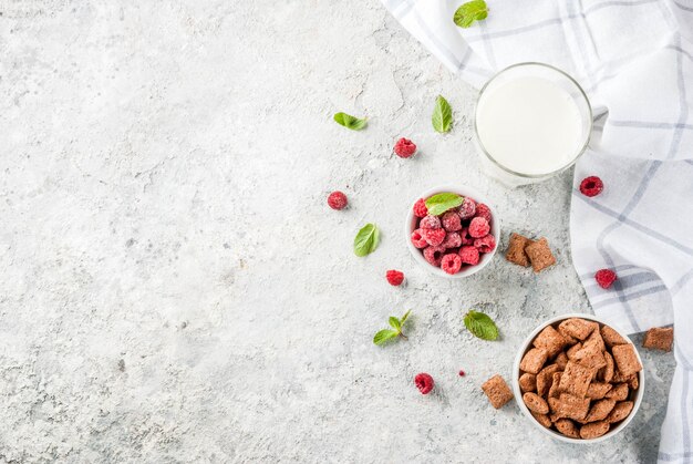 Ingredientes saludables para el desayuno. Cereal de desayuno, vaso de leche o yogurt, frambuesas