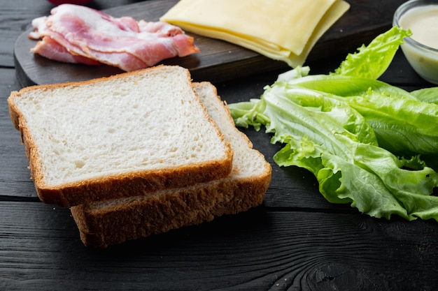 Ingredientes del sándwich club, sobre mesa de madera negra