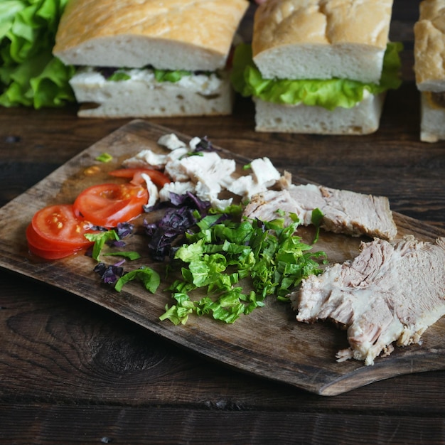 Ingredientes de sándwiches en una tabla de madera sobre un fondo oscuro