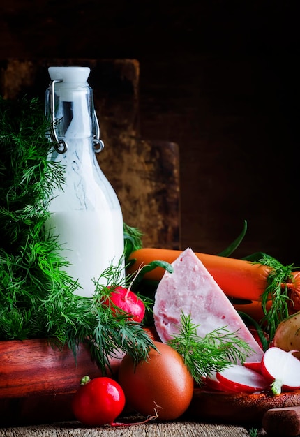 Ingredientes para sopa fría con verduras, hierbas y productos cárnicos, mesa de madera antigua, enfoque selectivo.