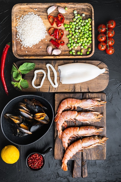 Ingredientes tradicionais da paella valenciana de frutos do mar com camarões, mexilhões, arroz e temperos no preto