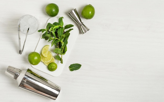 Ingredientes y utensilios de bar para hacer un cóctel mojito con cubitos de hielo, menta fresca y lima