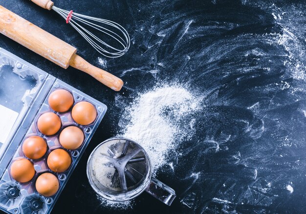 Ingredientes y utensilios para hornear en el tablero negro, vista superior