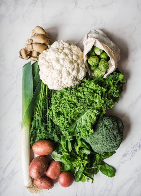 Ingredientes veganos saludables para cocinar. Varias verduras y hierbas limpias en el fondo de mármol. Productos del mercado sin plástico. Lay Flat