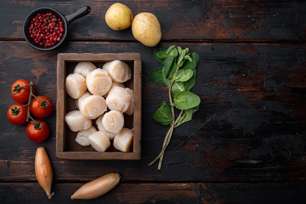 Ingredientes de vieiras chamuscadas chisporroteando, vista superior, sobre mesa de madera oscura