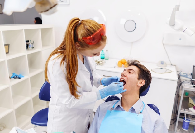 Ingwer-Zahnarzt untersucht die Zähne eines jungen Patienten