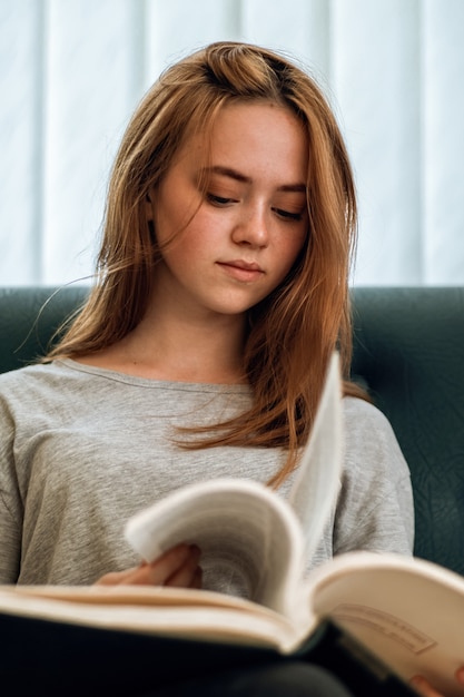 Ingwerhaarmädchen mit lässiger Kleidung, die ein Buch liest