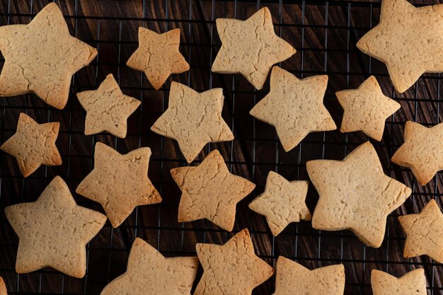 Ingwerplätzchen in Sternenform auf dem Grill neben Tannenzweigen und einer Tasse Tee