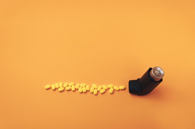 Foto inhalador de asma negro con aerosol de partículas hecho de pastillas amarillas preparaciones de vitaminas colorantes f