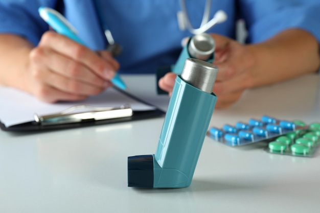 Inhalator gegen Krankenschwester, die am Tisch sitzt und schreibt