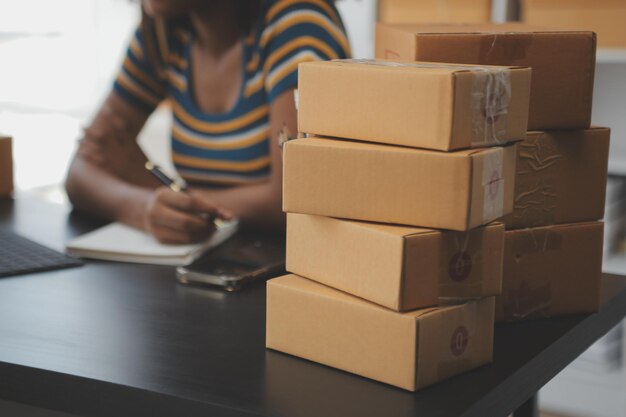 Foto iniciantes de pequenas empresas proprietárias de pme mulheres empresárias escreva o endereço na caixa de recibo e verifique as encomendas on-line para se preparar para empacotar as caixas vender aos clientes sme ideias de negócios on-line