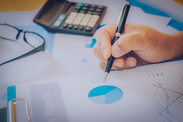 Início do processo de trabalho. Empresário trabalhando na mesa de madeira com novo projeto de finanças. Caderno moderno na mesa. Caneta segurando a mão