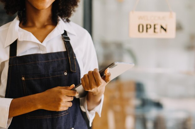 Inicio exitoso propietario de una pequeña empresa sme beauty girl stand con tablet smartphone en cafetería restaurante Retrato de mujer asiática bronceada barista cafe propietario SME empresario vendedor concepto de negocio