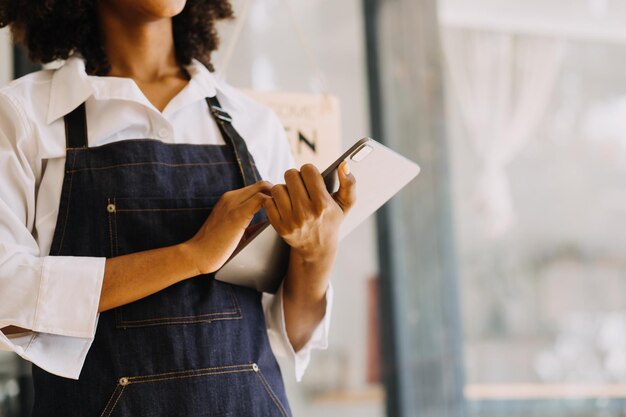 Inicio exitoso propietario de una pequeña empresa sme beauty girl stand con tablet smartphone en cafetería restaurante Retrato de mujer asiática bronceada barista cafe propietario SME empresario vendedor concepto de negocio