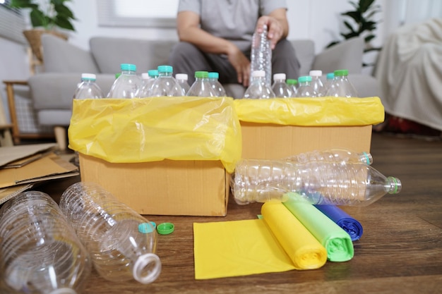 Inicio reciclar eco verde concepto cero Hombre tirando una botella de plástico vacía en un contenedor de reciclaje con bolsas de basura amarillas en casa