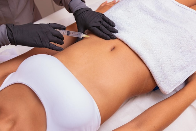 Foto injeção plástica no salão spa. a esteticista faz a injeção na barriga do paciente. o conceito de rejuvenescimento.