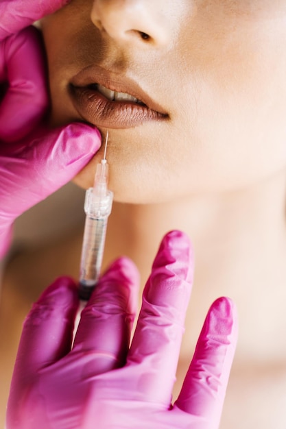 Injeções de aumento de lábios closeup nos lábios para garota atraente Cosmetologista injetando ácido hialurônico nos lábios para aumento na clínica médica Tratamento facial rejuvenescedor cosmético