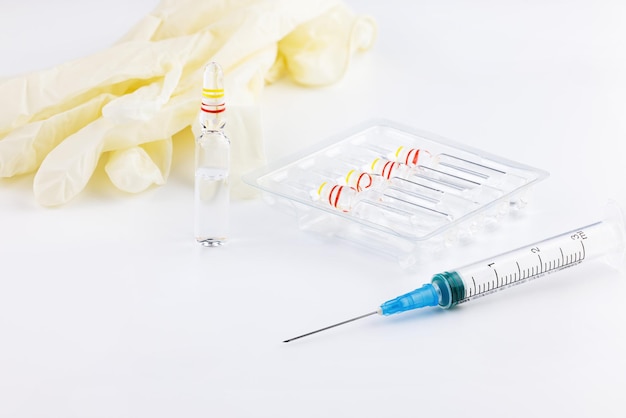 Injektionsspritze auf dem Hintergrund von Ampullen mit Injektionsmedizin und medizinischen Handschuhen