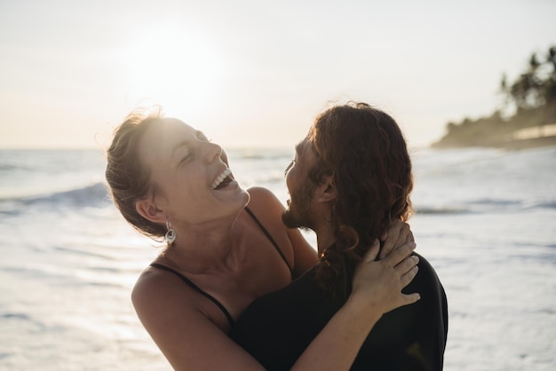 Inmitten der Ozeanwellen umarmt ein Mann eine Frau und sie lachen fröhlich