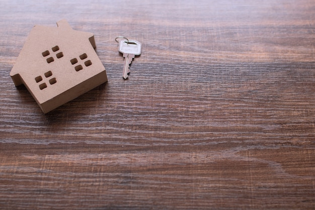 Inmuebles con modelo de casa y llave en mesa de madera.