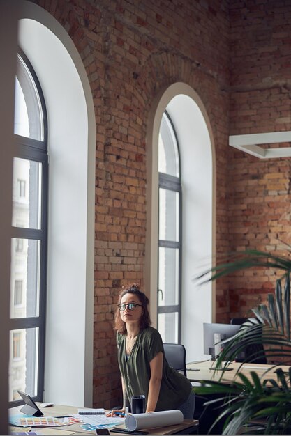 Innenarchitekt oder Architekt in Freizeitkleidung mit unordentlicher Frisur, die während der Arbeit in die Kamera schaut