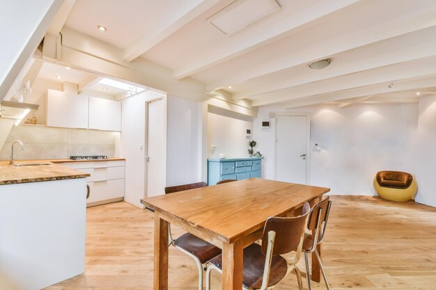 Innenarchitektur der modernen Loft-Wohnung mit offener Küche im minimalistischen Stil und geräumigem Essbereich mit Tisch und Stühlen