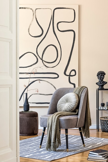 Innenarchitektur des Wohnzimmers mit stilvollem grauem Sessel, abstrakten Gemälden an der Wand, Blumen in Vase, Kissen, Plaid und eleganten persönlichen Accessoires. Beige-Konzept. Moderne Homestaging.
