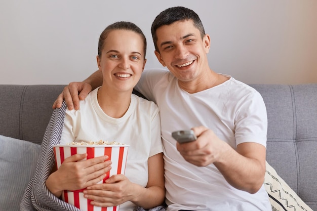 Innenaufnahme eines attraktiven jungen Paares, das gemeinsam Filme sieht, während es zu Hause auf dem Sofa sitzt