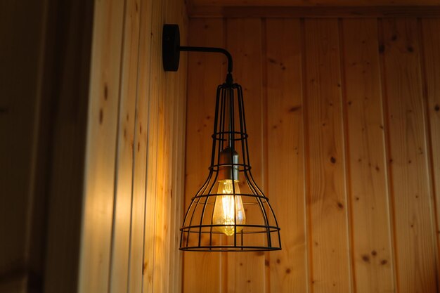 Innendetails Stilvolle skandinavische Komposition aus schwarzem BH mit Vintage-Edison-Lampe und Holz