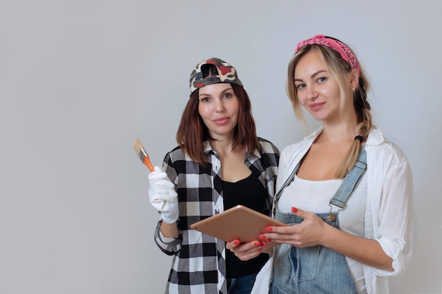 Inneneinrichtung. Zwei süße Mädchen, Designer und Maler machen Reparaturen im Haus. Ein Team von Dekorateuren.