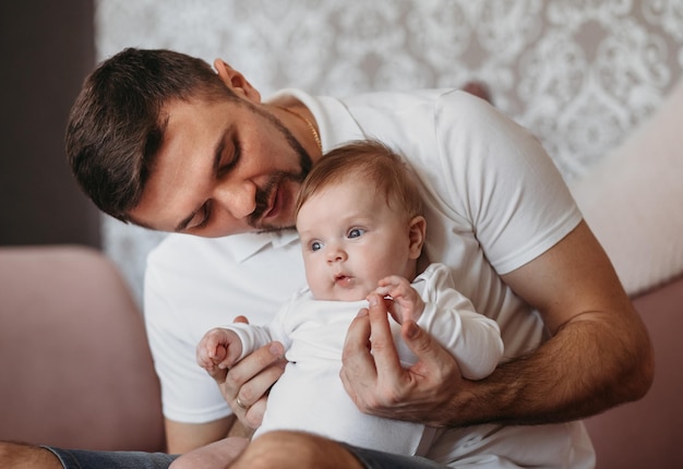 Innenporträt des jungen Vaters, der seine kleine Tochter umarmt