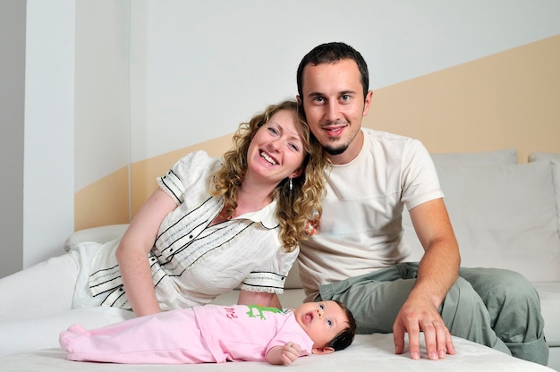 Innenporträt mit einer glücklichen jungen Familie und einem süßen kleinen Baby