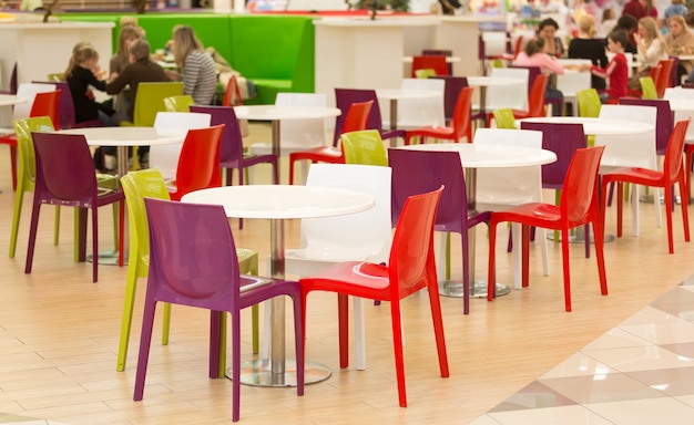 Innenraum des öffentlichen Essbereichs mit farbigen Plastikstühlen und Tischen