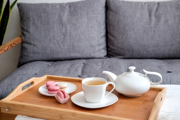 Innenraum des Wohnzimmers mit Tasse Tee auf einem Serviertablett auf einem Couchtisch Sofa Zimmerpflanze Gemütliches Konzept