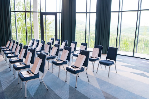Foto innenraum eines großen modernen konferenzraums mit geschenken und kopfhörern auf den stühlen für die teilnehmer vor beginn eines geschäftsseminars