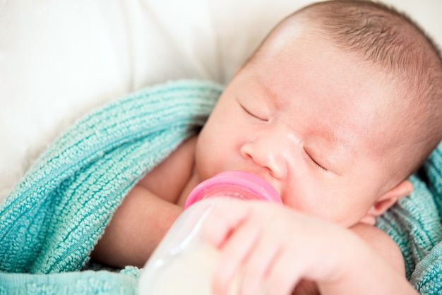 Inocente bebé recién nacido durmiendo bebiendo leche de biberón