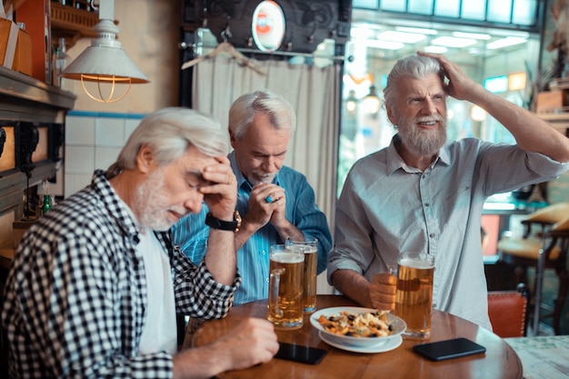 Insatisfecho después de mirar. tres jubilados que se sienten insatisfechos después de ver fútbol en el pub