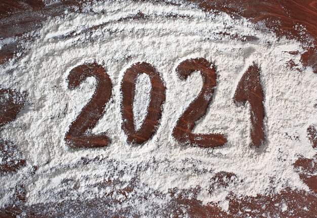 Inschrift 2021 auf Weißmehl auf Holztisch