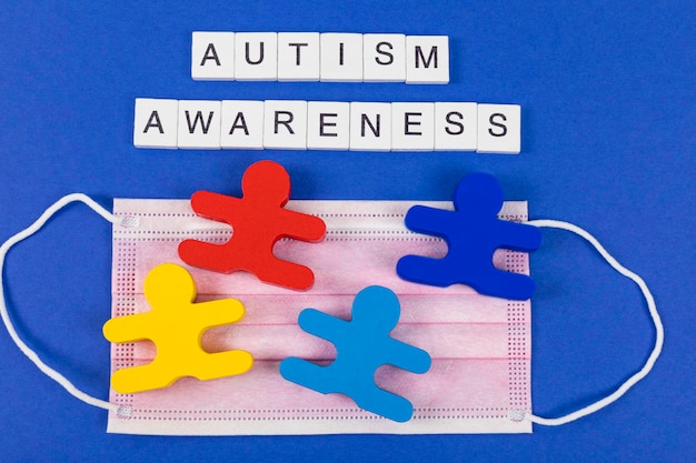 Foto inschrift autismusbewusstsein mit medizinischer maske und vier holzspielzeug